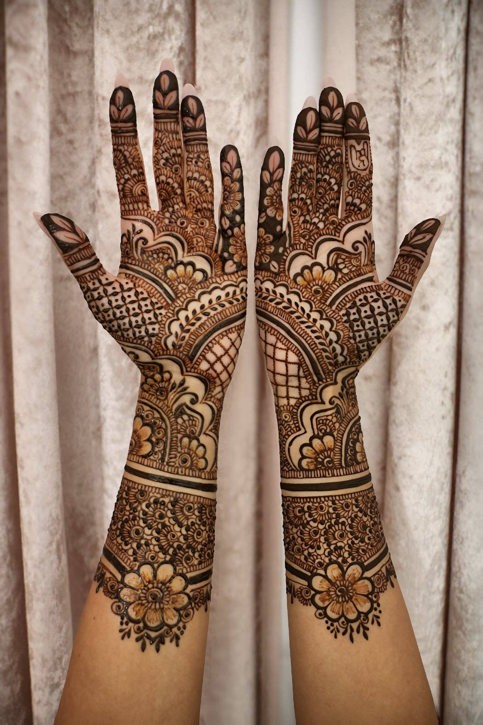 Elegant bridal henna on the backs of both hands and arms against a sheer curtain
