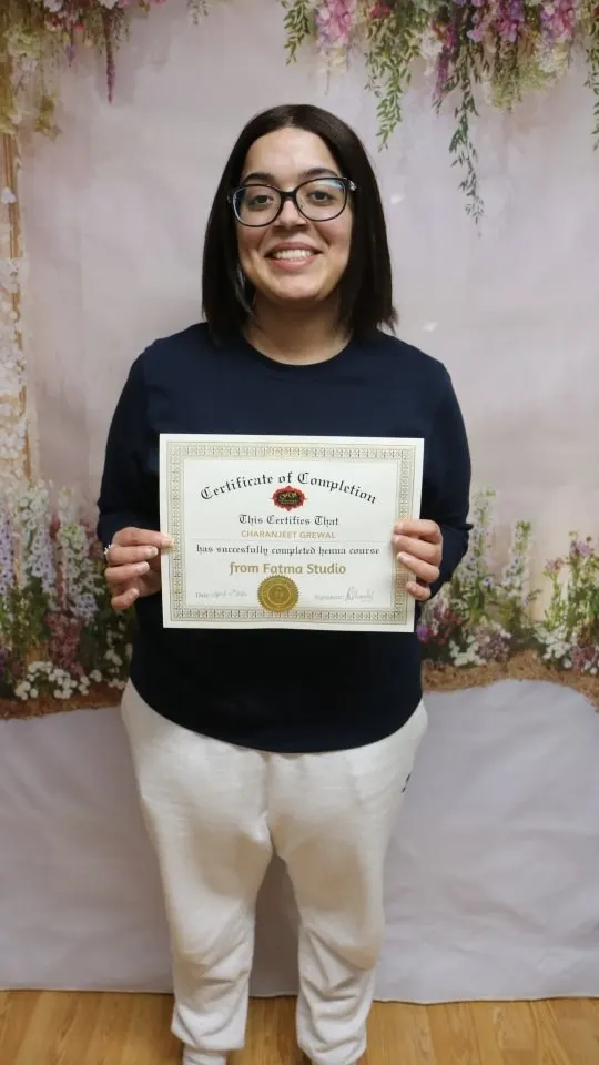 A student holding her henna course certificate