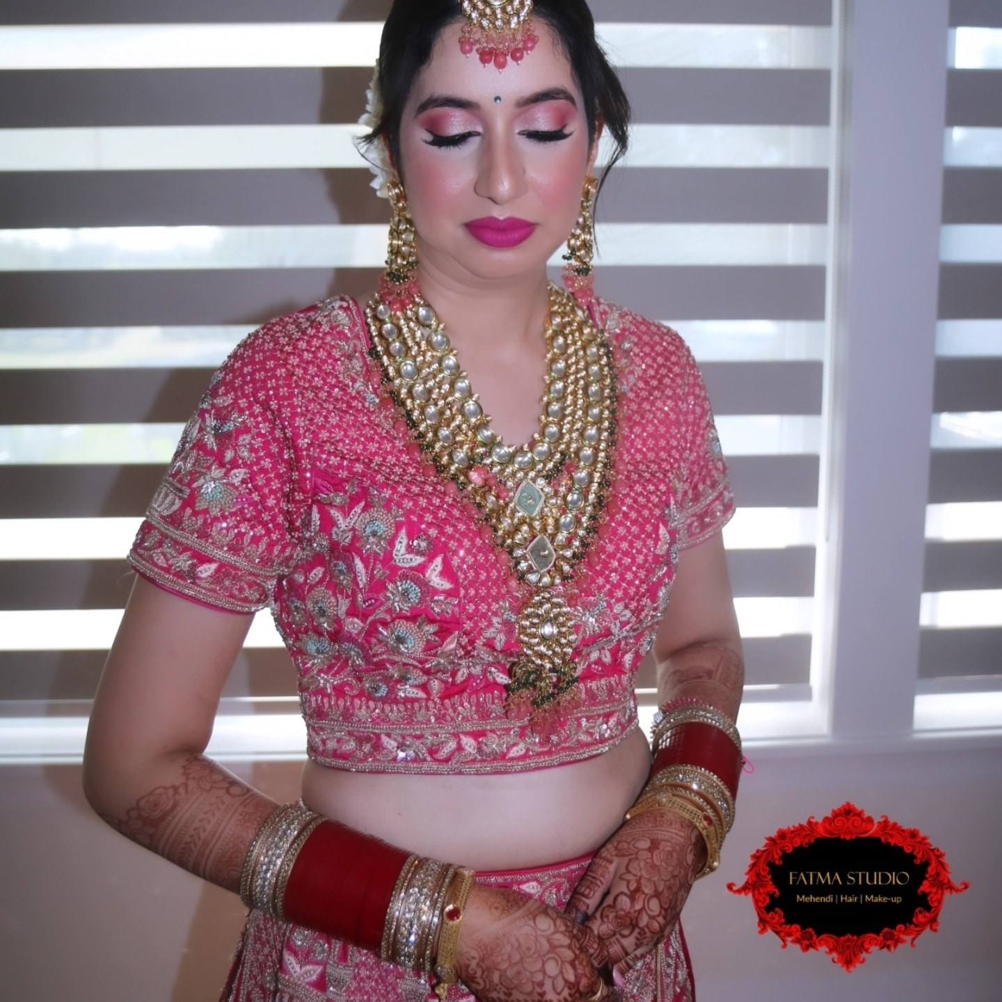 Bride in pink with kundan necklace and chooda, finished bridal makeup and hair