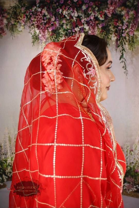 Bride under a red sheer veil with gold borders