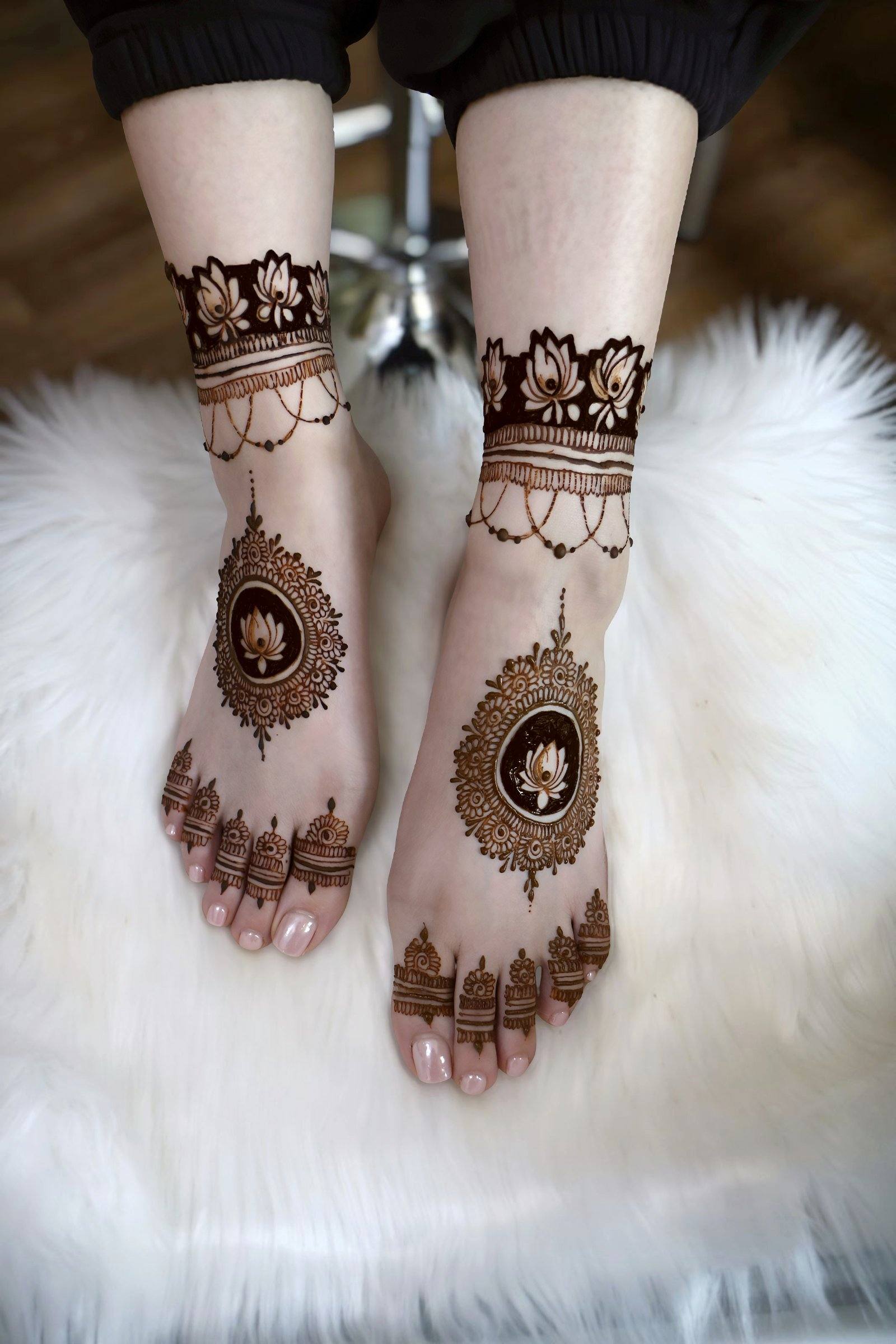 Bridal henna on feet with medallion and anklet-style designs on white fur