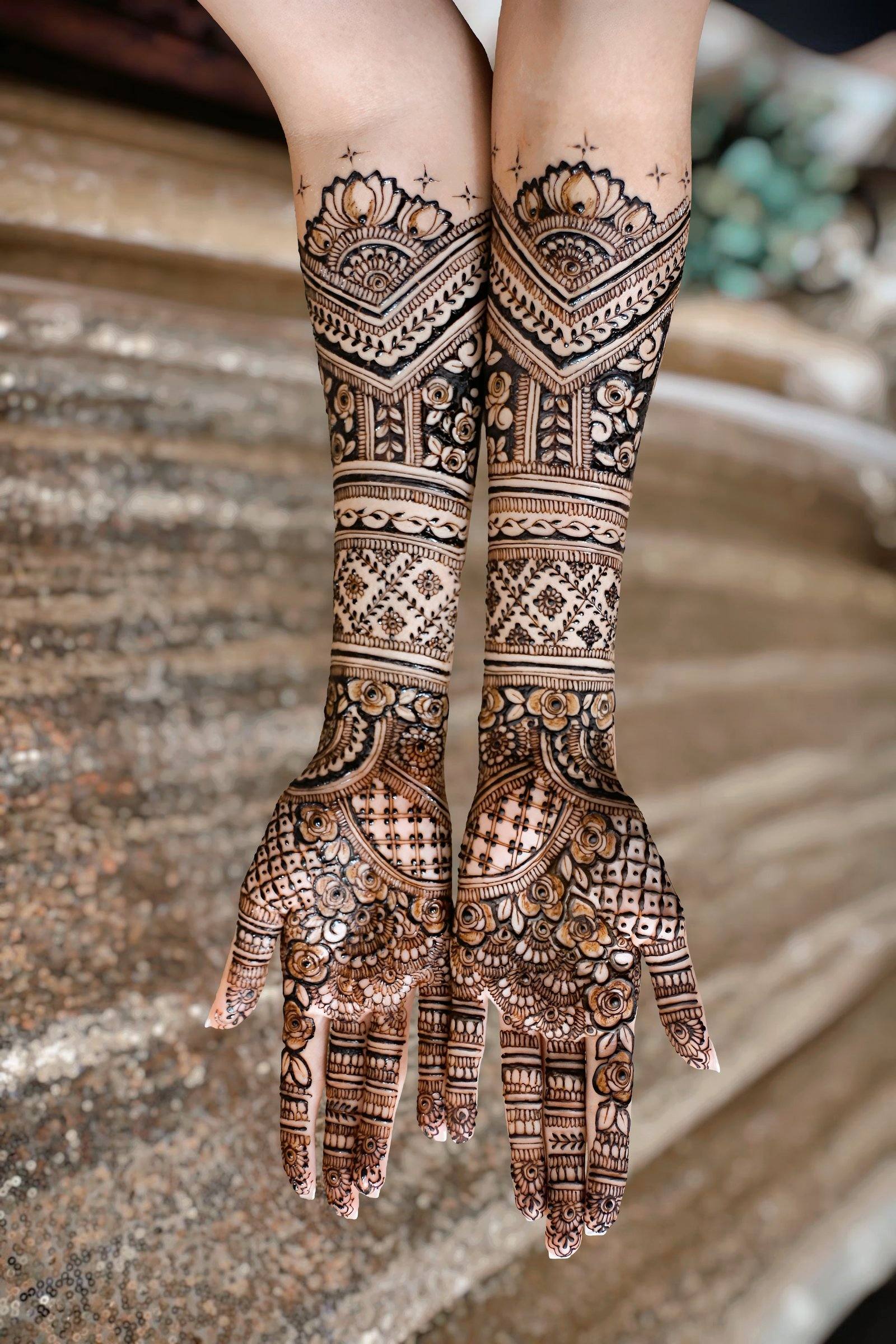 Full-length bridal henna on both arms against a shimmering backdrop
