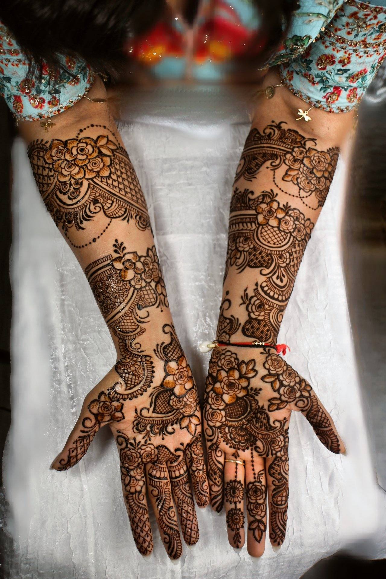 Floral bridal henna on arms with a red thread bracelet
