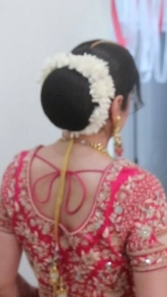 Bridal bun with a white flower gajra over a red blouse